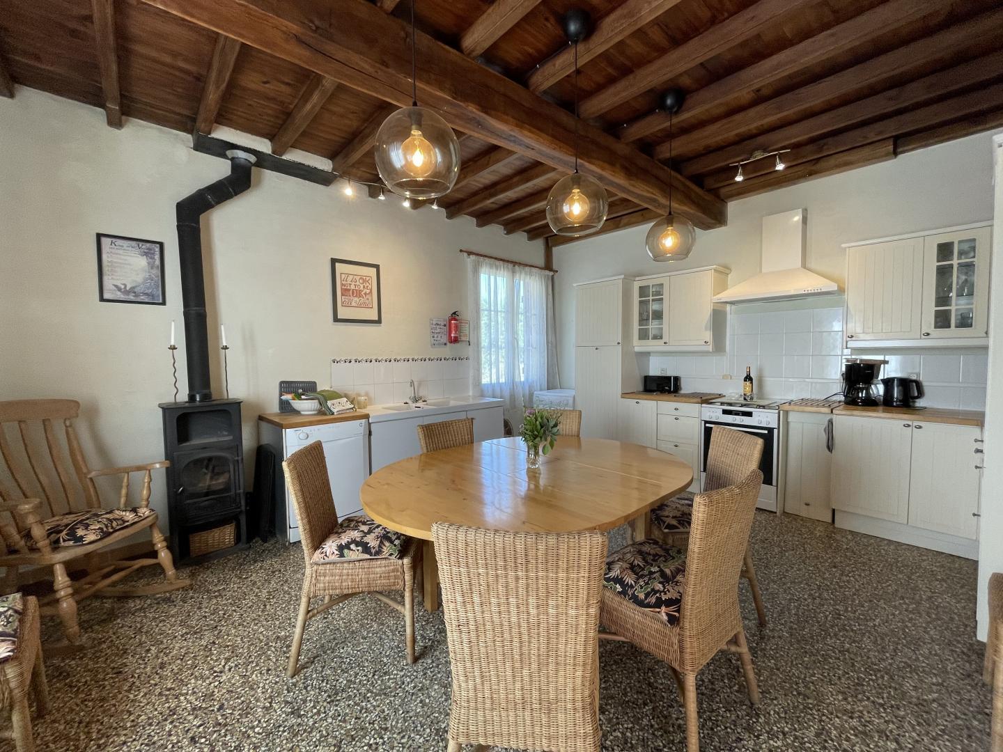Fully equipped farmhouse kitchen with dining table, wood-burning stove and pendant lighting at Maison Lajus, South West France