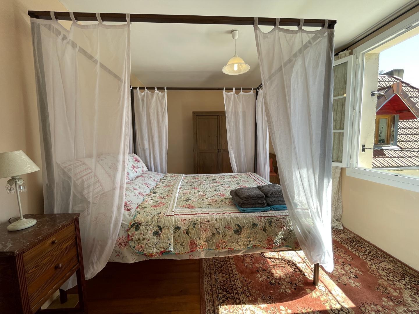 Master bedroom with four-poster bed, en-suite and garden views at Maison Lajus farmhouse gîte, Pyrénées-Atlantiques