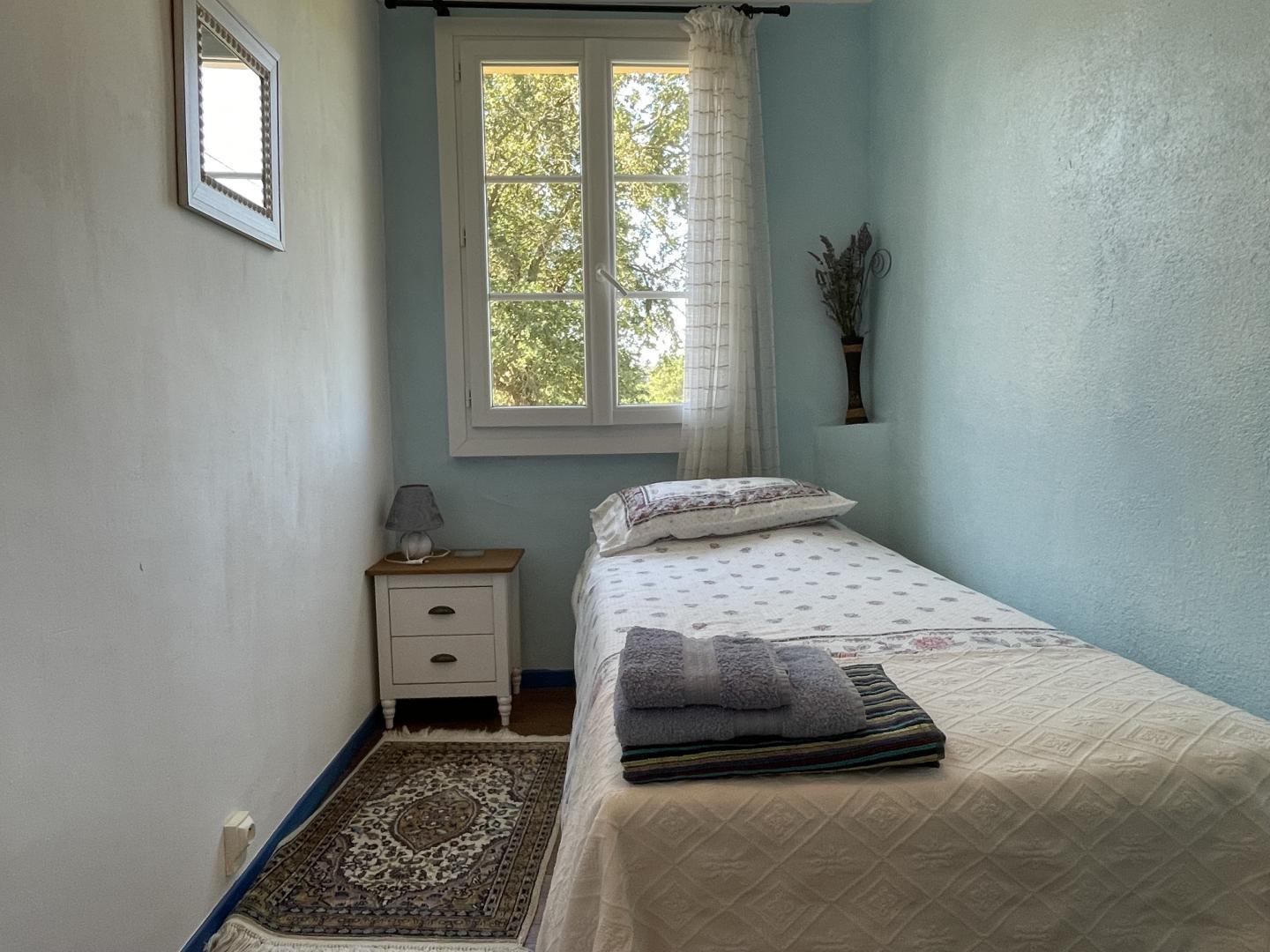 Cosy single bedroom with blue walls, garden window and bedside table at Maison Lajus gîte, Bassillon-Vauzé, France