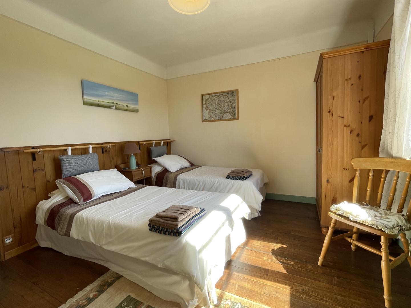 Second twin bedroom with wooden floors, pine wardrobe and bright window at Maison Lajus farmhouse, Pyrénées-Atlantiques